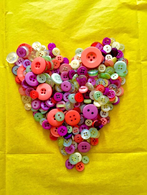 Directly above shot of multi colored buttons in heart shape on table