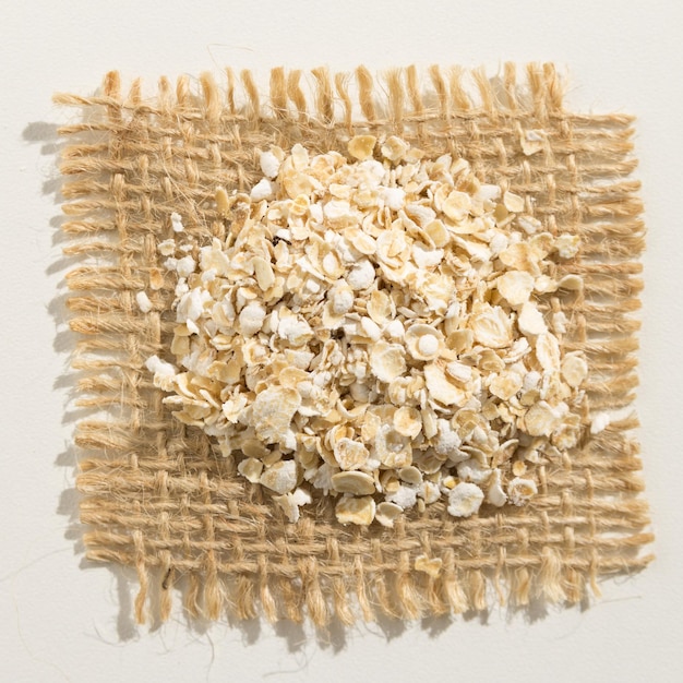 Photo directly above shot of oat flakes on jute over white background