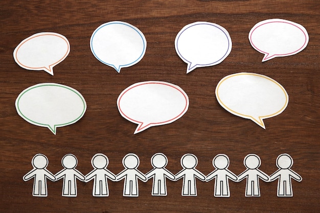 Directly above shot of paper chain and speech bubbles on wooden table