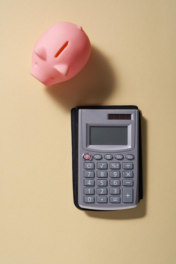 Photo directly above shot of piggy bank and calculator on yellow background
