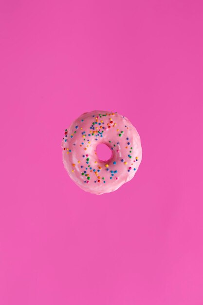 Photo directly above shot of pink doghnut against colored background