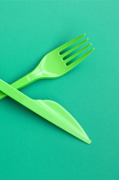 Directly above shot of plastic fork and knife on green background