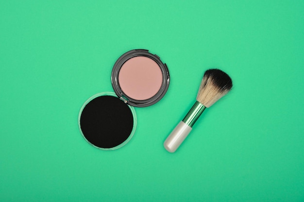 Directly above shot of powder compact and brush on green background