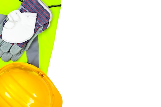 Directly above shot of protective gloves with hardhat and reflective clothing over white background