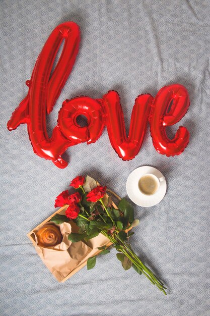 Photo directly above shot of roses with breakfast on bed