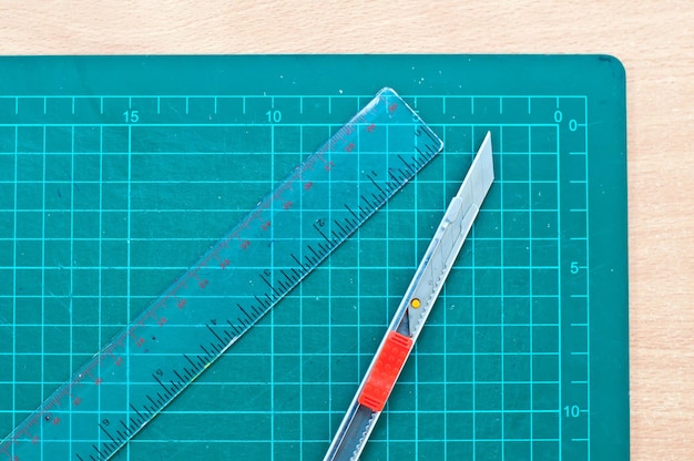 Photo directly above shot of ruler and utility knife on paper