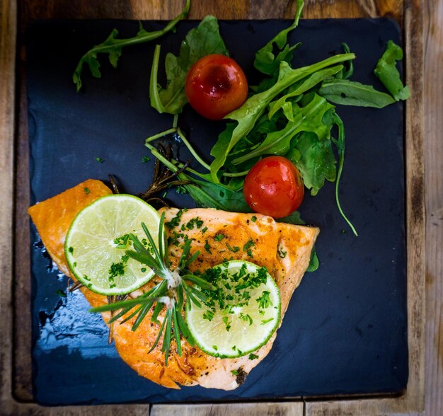 Foto direttamente sopra il tiro di salmone con fetta di lime e pomodoro allegro servito su ardesia