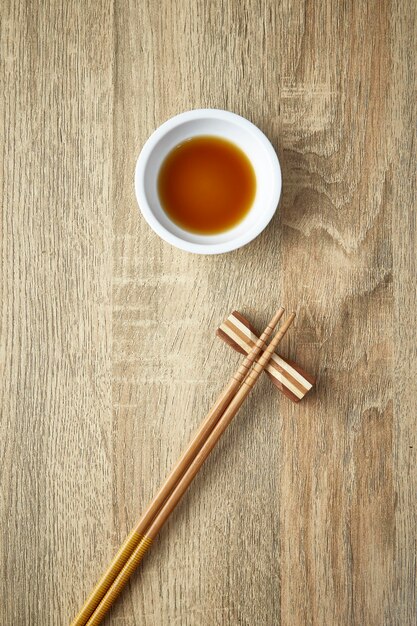 Photo directly above shot of sauce in bowl and chopsticks on rest at table