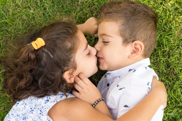 Photo directly above shot of siblings lying down on grassy field