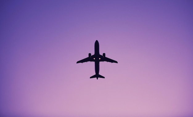 Photo directly below shot of silhouette airplane flying in clear purple sky
