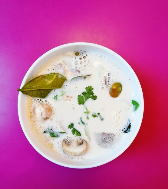 Directly above shot of soup in bowl over pink background