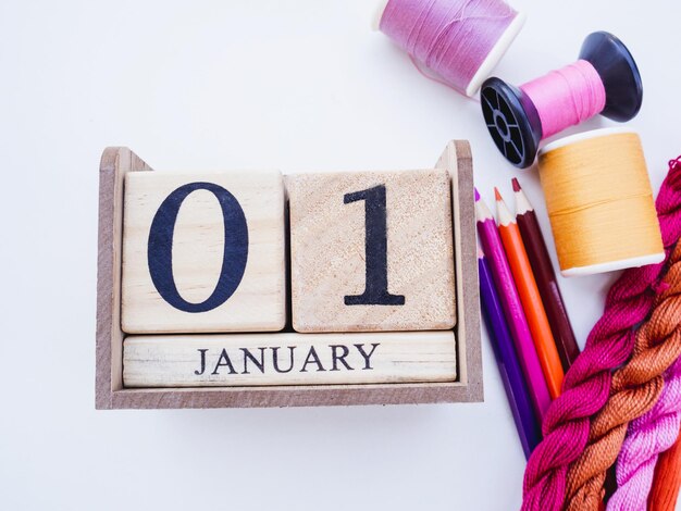 Photo directly above shot of spool with calendar an and tape measure over white background