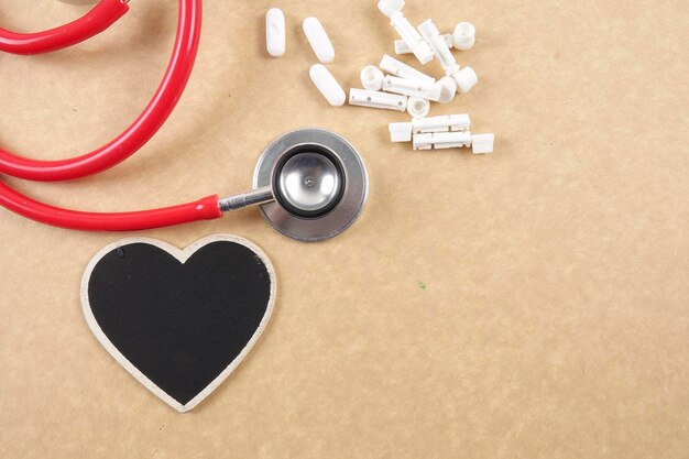 Directly above shot of stethoscope with heart shape and medicines on brown table