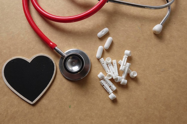 Photo directly above shot of stethoscope with heart shape and medicines on brown table