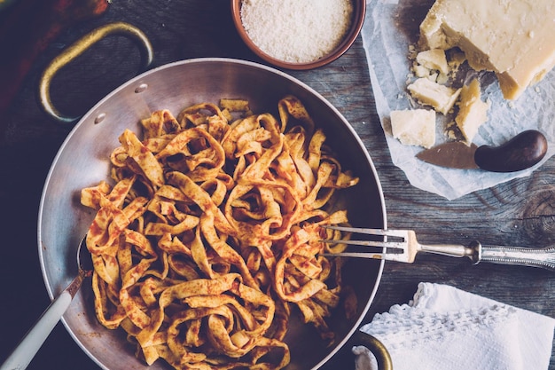 Foto direttamente sopra il colpo di tagliatelle in padella con formaggio parmesano su tavola