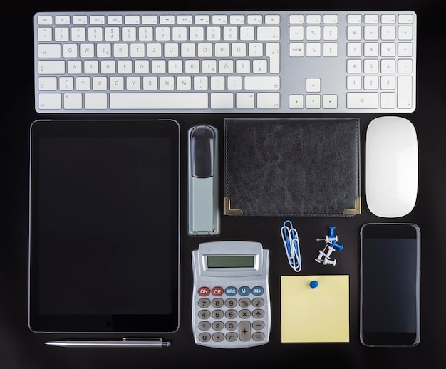 Photo directly above shot of technologies and office supplies on black background