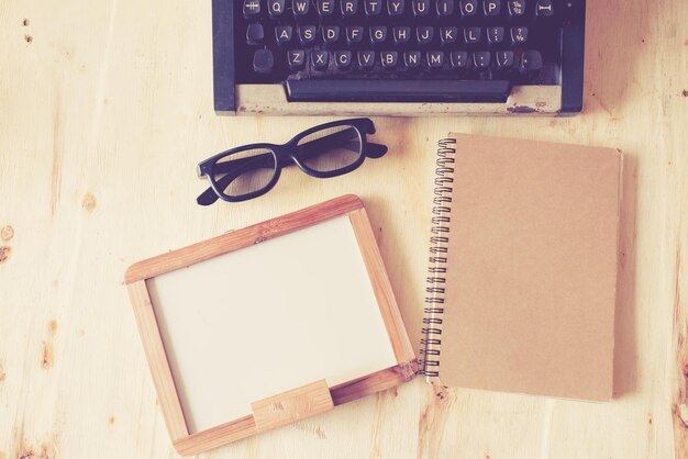 Directly above shot of typewriter with book and eyeglasses on table