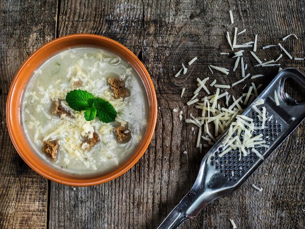 Foto direttamente sopra il colpo di zuppa di verdure con crouton e formaggio grattugiato su un tavolo di legno