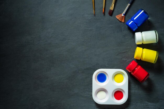 Photo directly above shot of watercolor paints in container with pallet and paintbrush on table