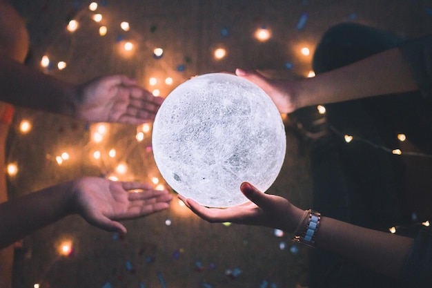 Foto direttamente sopra la foto di una donna che dà una palla di cristallo illuminata a un amico