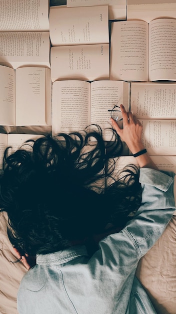 directly above shot of woman lying on bed while reading book at home