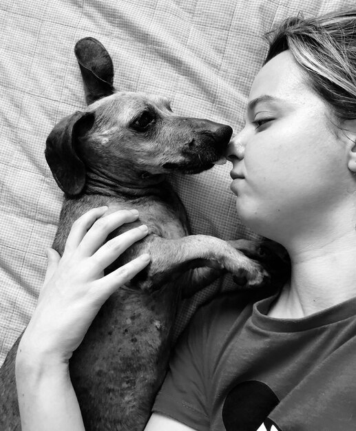 家のベッドで犬を飼っている女性の直接上の写真