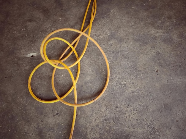 Photo directly above shot of yellow cable over concrete