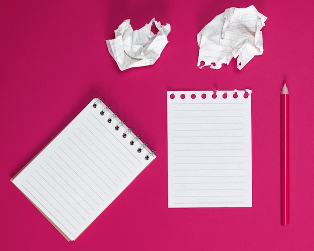 Directly above view of blank note pad and colored pencil on pink background