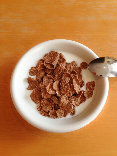 Photo directly above view of breakfast cereal served in bowl with spoon on table