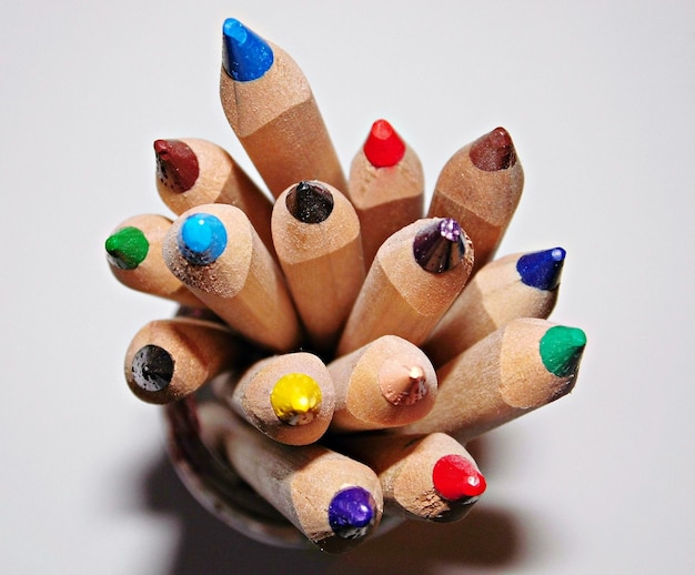 Directly above view of colored pencils in container on white background