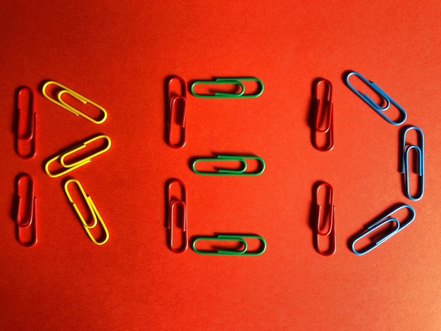 Photo directly above view of colorful paper clips on red background