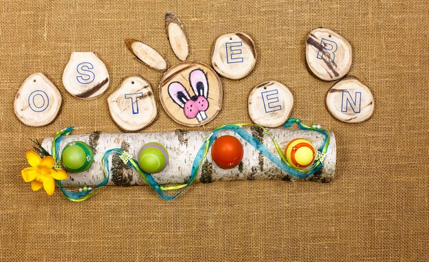 Photo directly above view of easter eggs and alphabet with rabbit head on jute