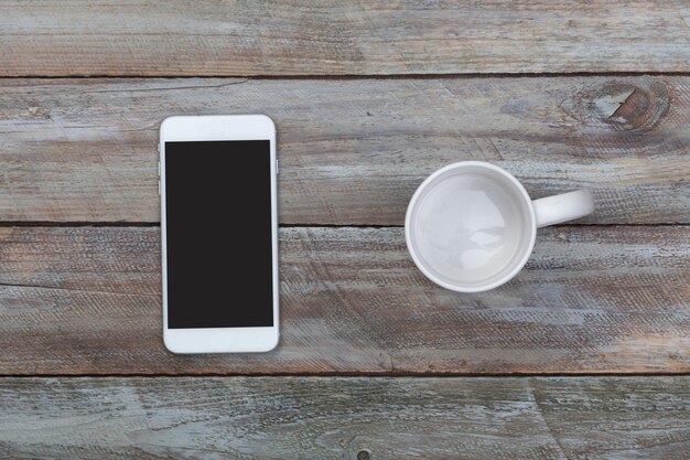 Foto visto direttamente sopra una tazza di caffè vuota e un telefono cellulare sul tavolo