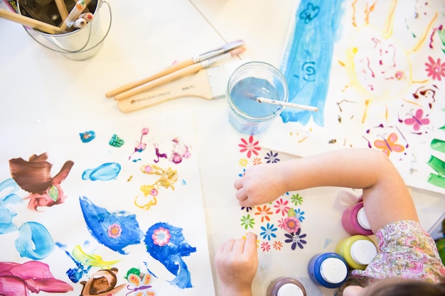 directly above view of girl making drawing on desk at home