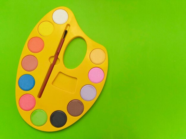 Photo directly above view of palette and paintbrush on colored background
