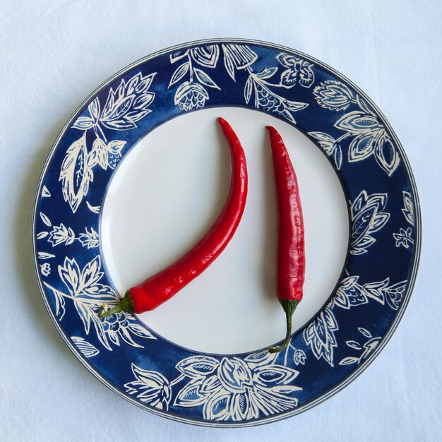 Photo directly above view of red chili peppers on plate over white background