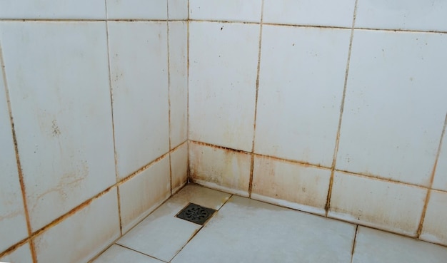 Dirt on the floor, stains on the walls, and corners of bathroom tiles white. Slippery and may