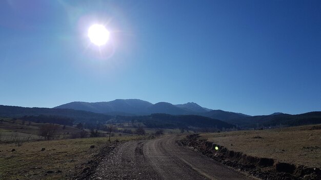 Dirt road along landscape against clear sky