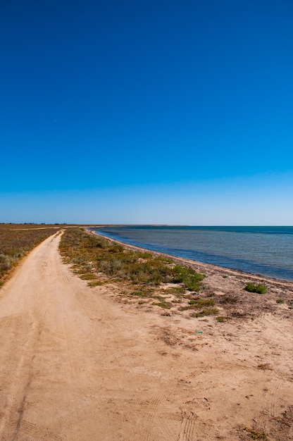 Dirt road along the salt lake against a clear blue sky