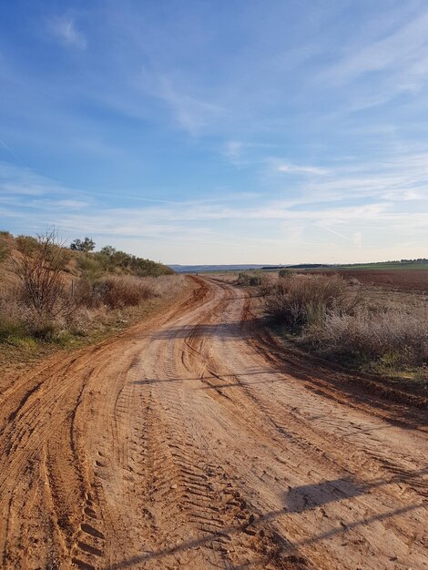 Photo dirt road amidst field against sky