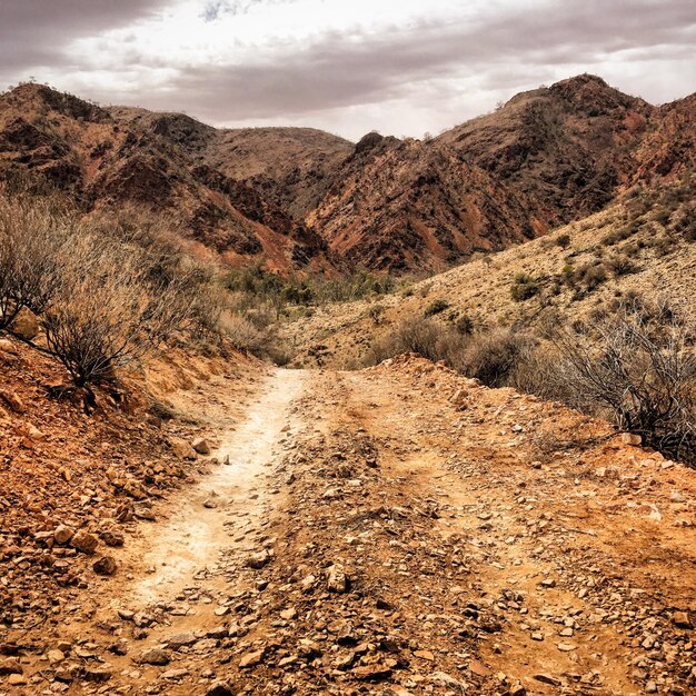 Photo dirt road leading towards mountains against sky