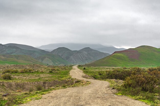 Dirt road in a mountainous area in cloudy weather