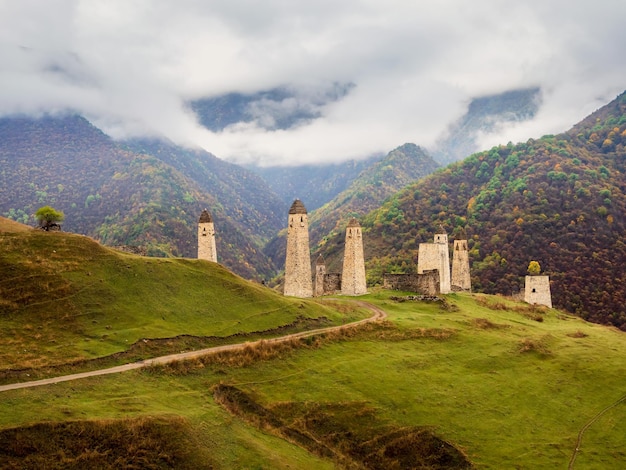 Dirt road to the tourist tower complex Majestic battle towers of Ingushetia Historical tourist attraction Medieval tower complex Erzi one of the largest medieval castletype tower villages