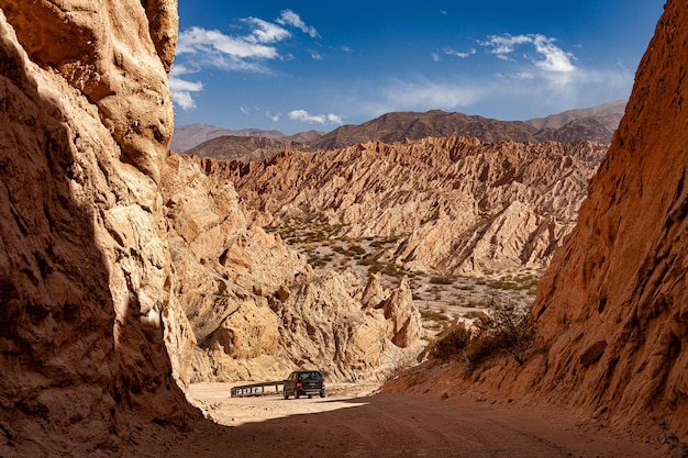Dirt road with car passing through the Quebrada de las Flechas in Argentina
