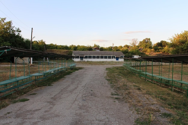 A dirt road with green benches and a building