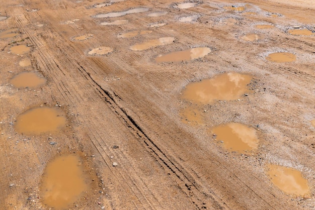 A dirt road with a lot of water holes