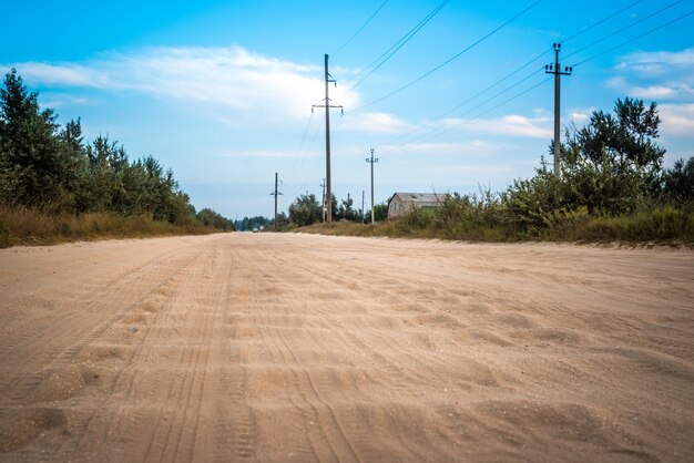 Dirt road with a sandy waves, cloud covering the blue sky