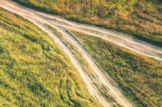 A dirt road with two arrows going down the middle of the grass