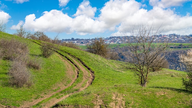 Dirt winding road on a green hill