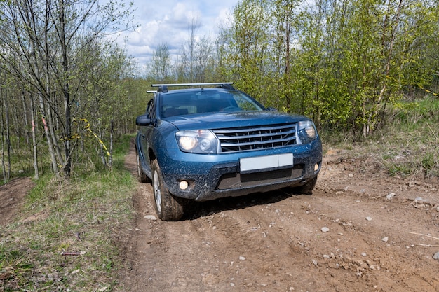 Dirty car on muddy road in a forest.